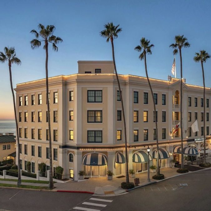 Exterior view of the Colonial Grand hotel near the beach with palm trees and coastal architecture.