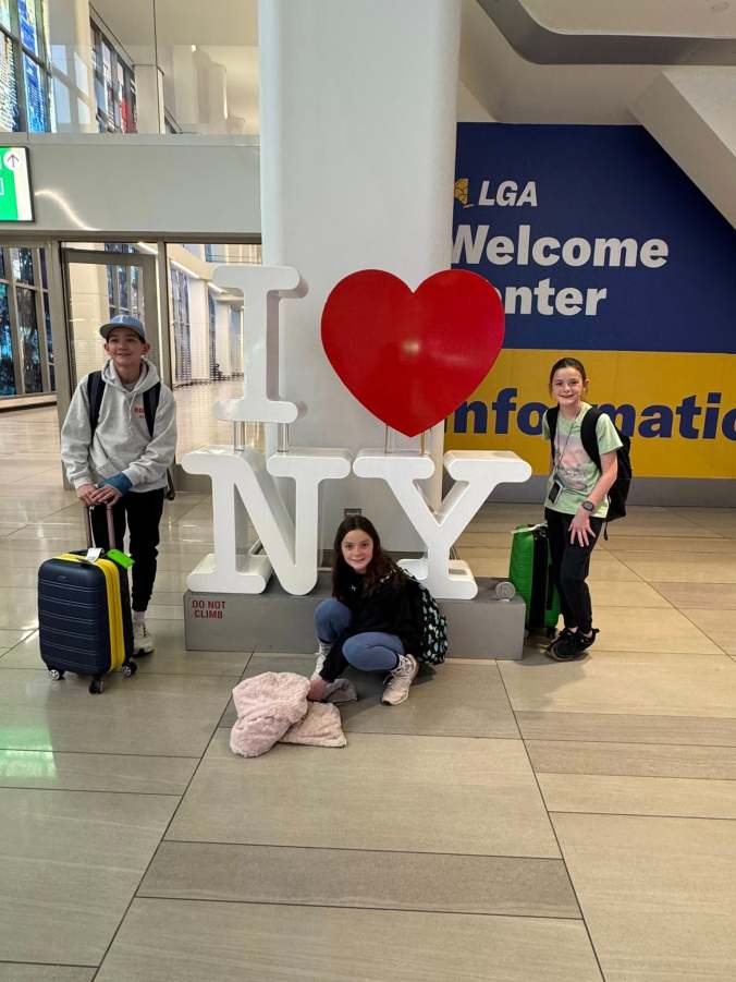 Kids with luggage at the airport starting a family trip to New York City