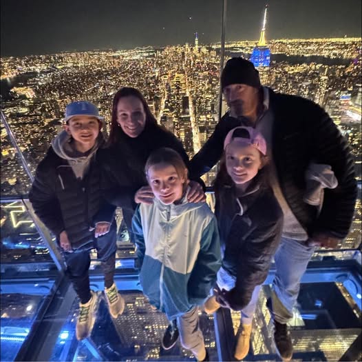 kids standing on glass floor at Summit One Vanderbilt overlooking New York City at night