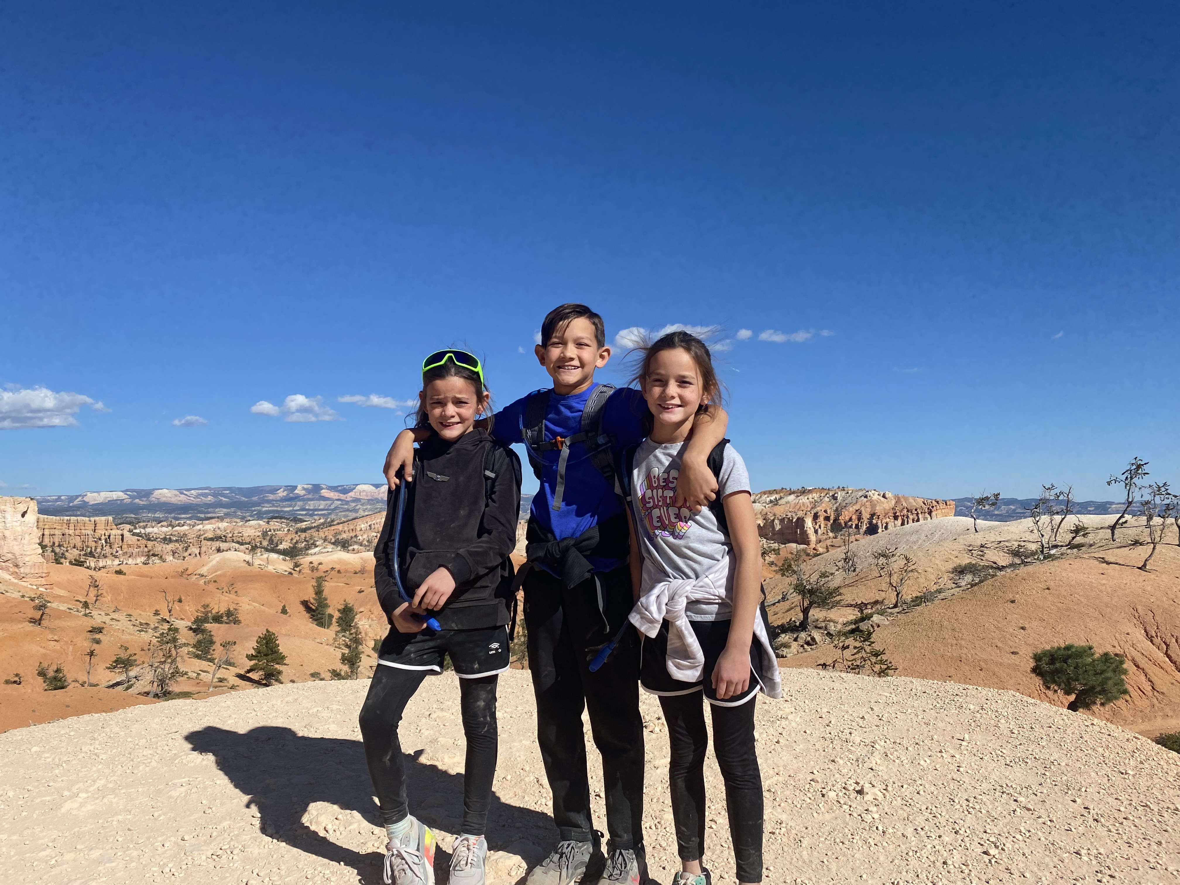Kids standing on the Queens Garden Navajo Loop trail at Bryce Canyon National Park with orange canyon walls around them