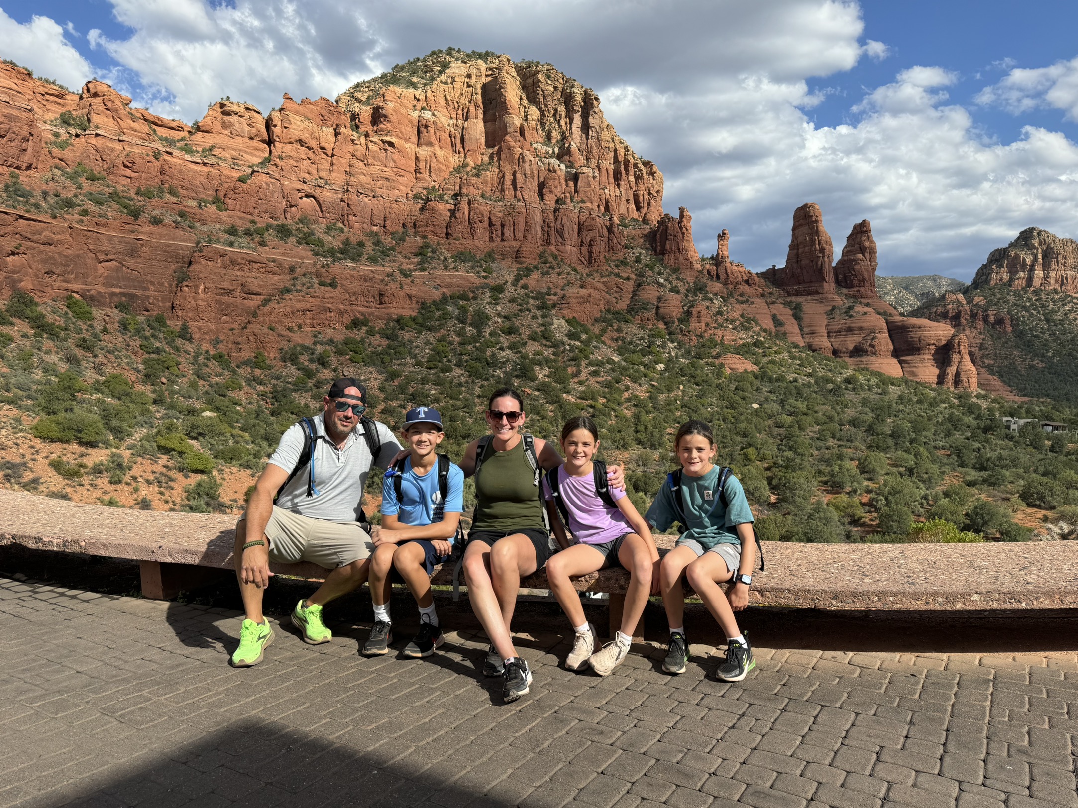 Family sitting together in front of red rock mountains in Sedona, Arizona during a scenic outdoor adventure