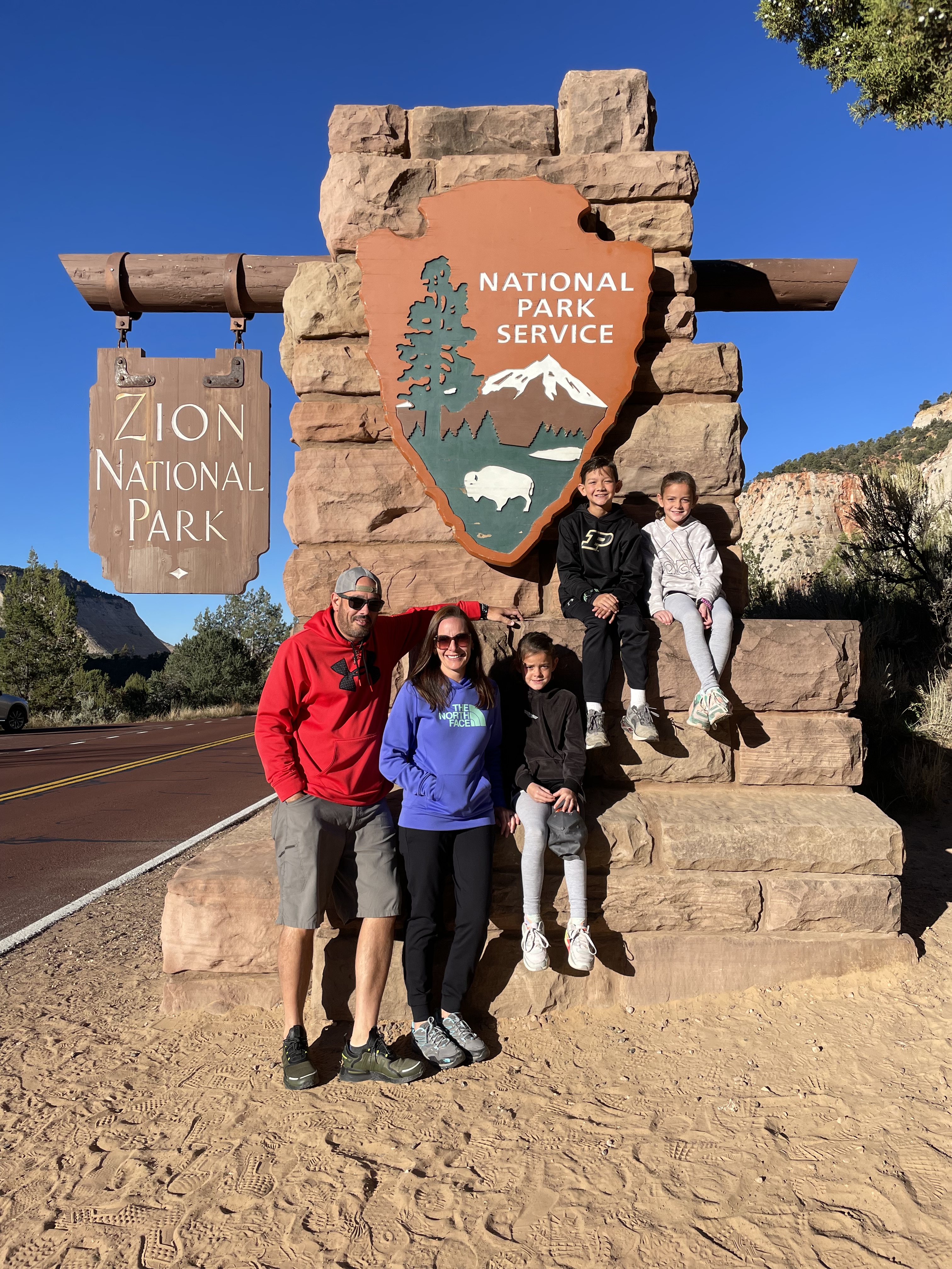 Family posing at the Zion National Park entrance sign