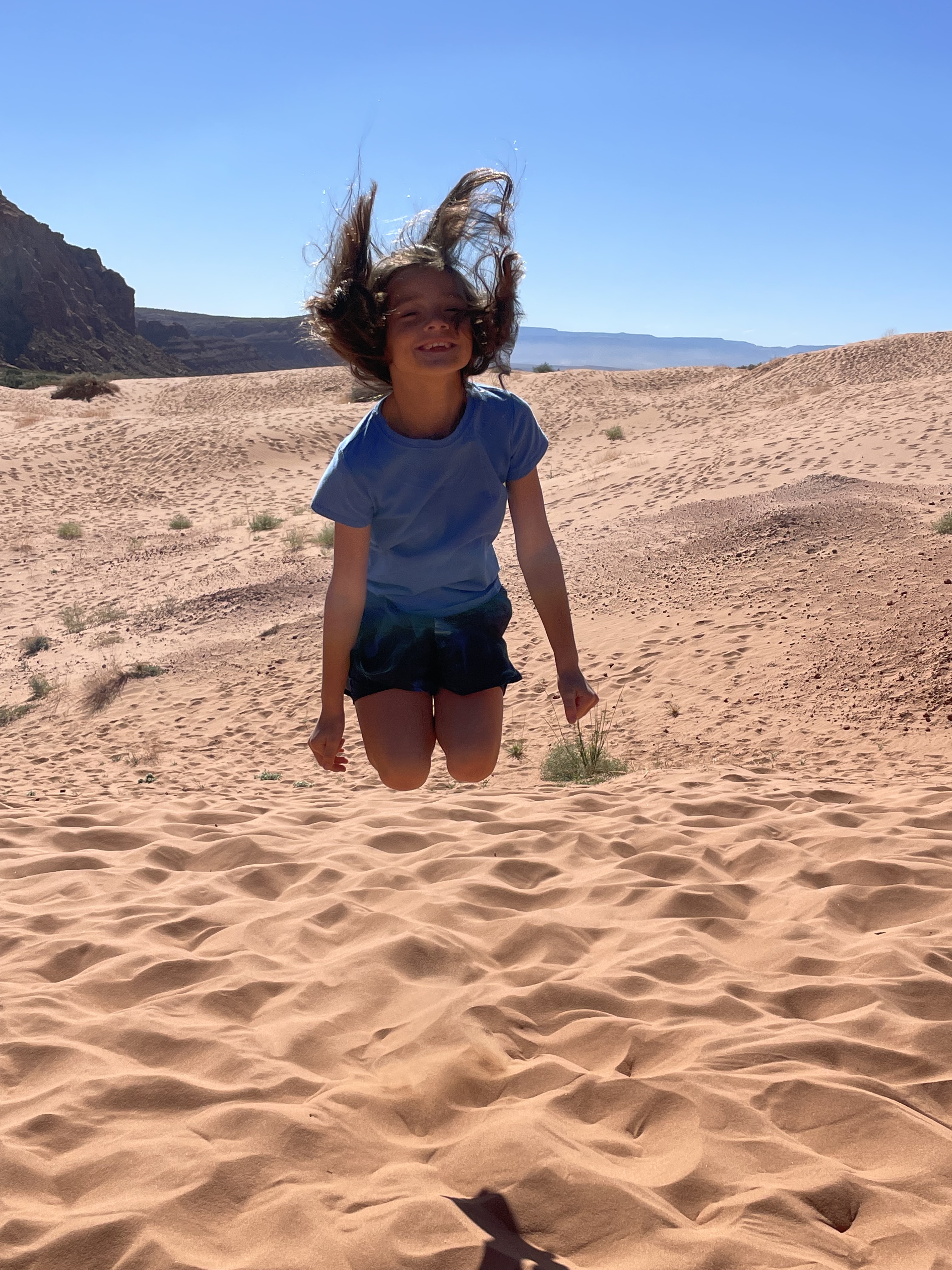 Child jumping in red sand dunes at Snow Canyon State Park