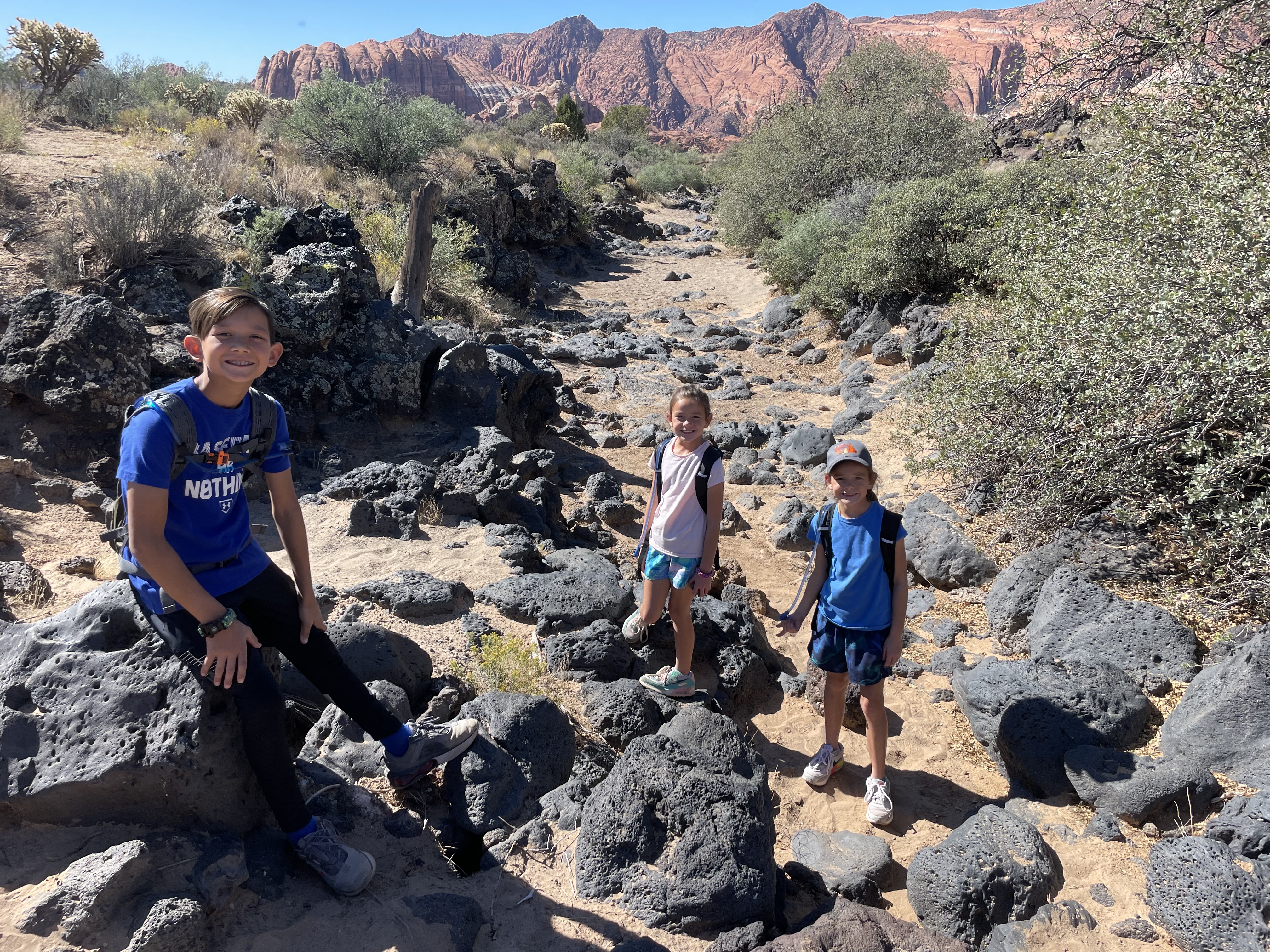 Kids hiking rocky lava trail at Snow Canyon State Park