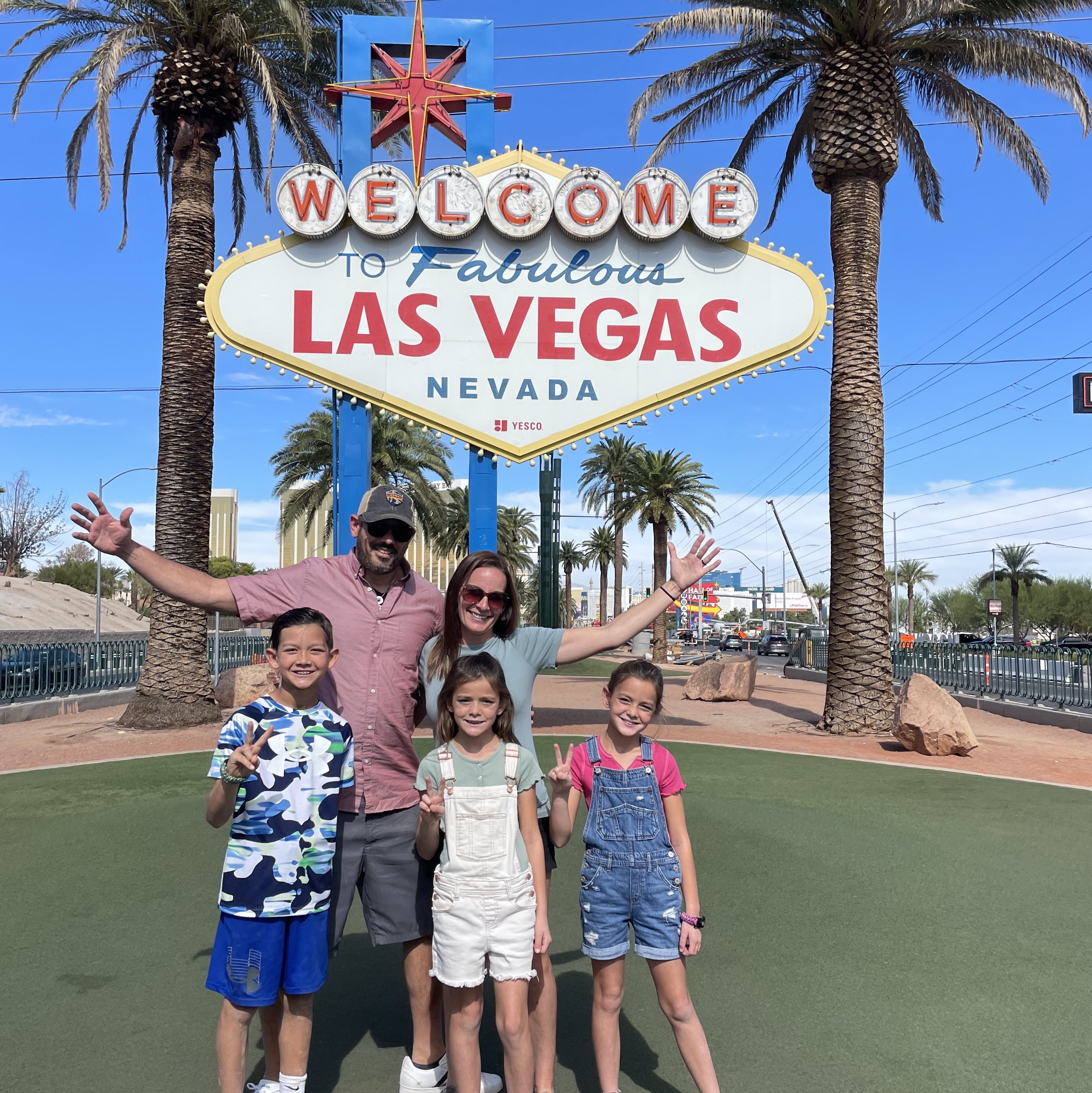 Family posing at the Welcome to Fabulous Las Vegas sign before a road trip to Zion and Bryce Canyon