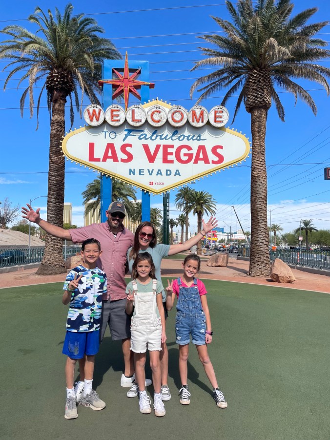 Family posing at the Welcome to Fabulous Las Vegas sign before a road trip to Zion and Bryce Canyon