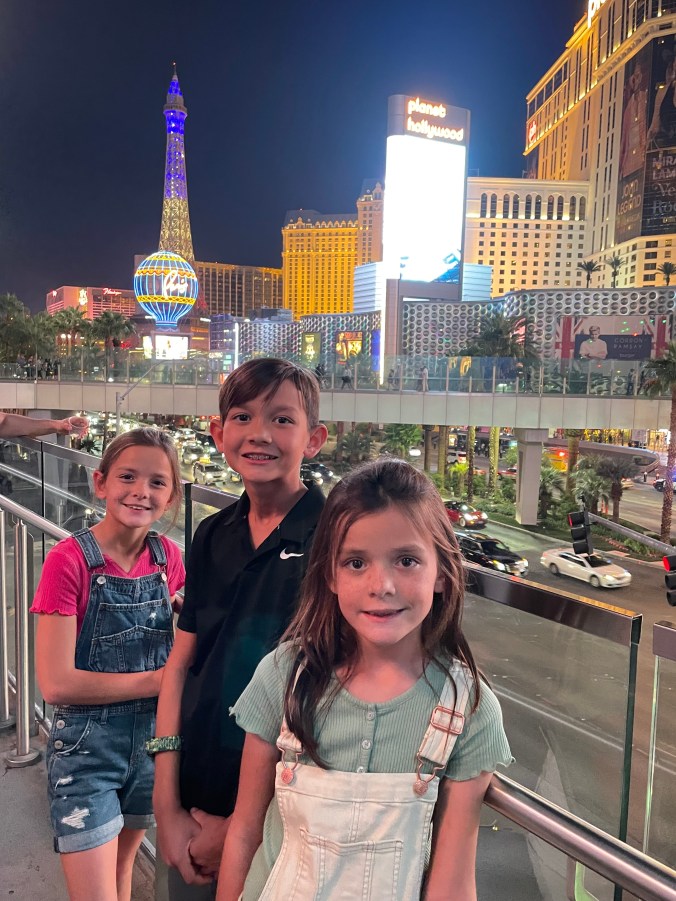 Kids walking along the Las Vegas Strip at night with bright lights and attractions