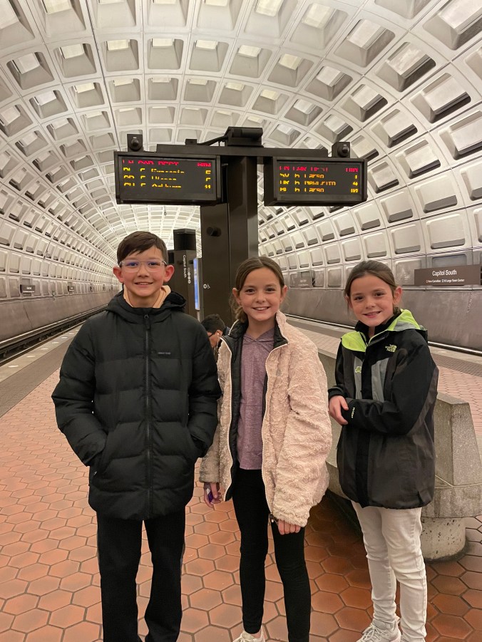Family with kids standing in subway station during travel day