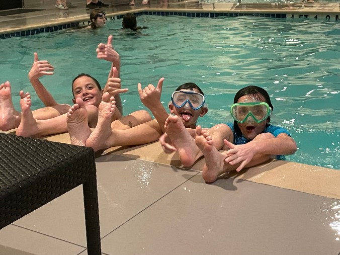 Kids relaxing and playing in a hotel pool during a family vacation