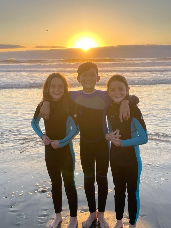 Kids wearing wetsuits swimming in the Pacific Ocean at a San Diego beach