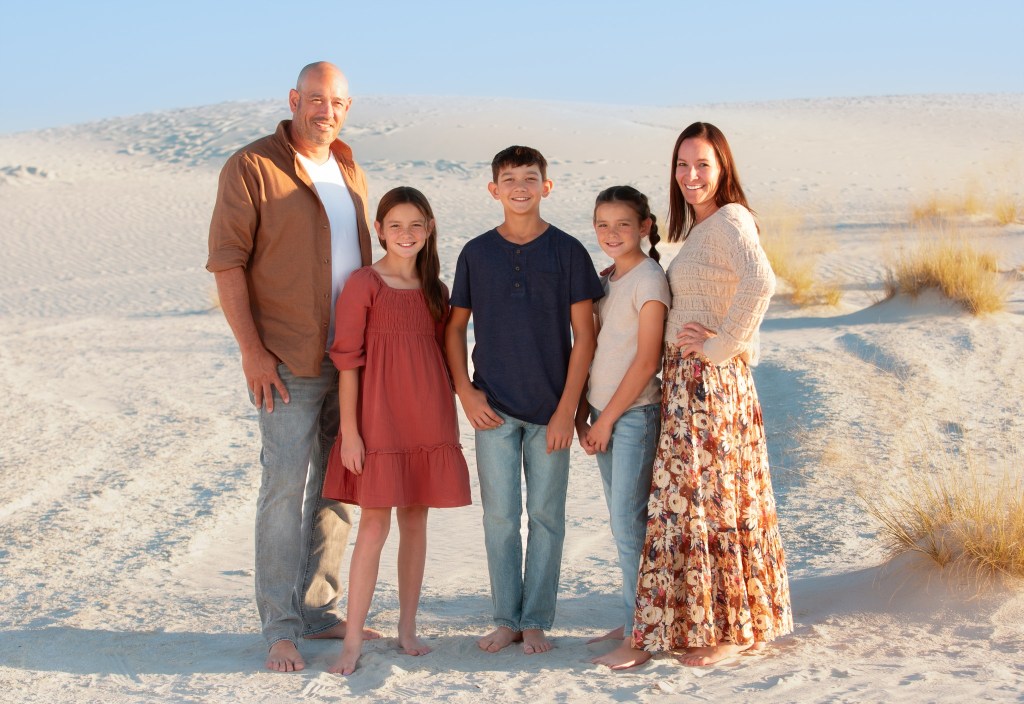 Family standing in White Sands National Park at sunset in New Mexico