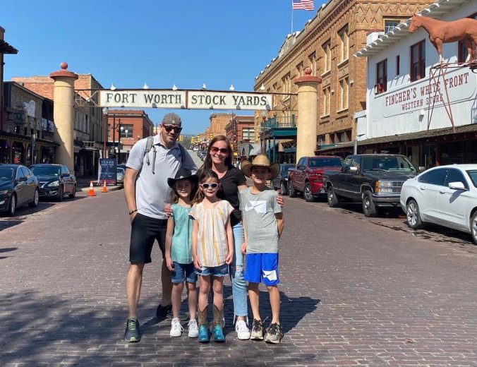 Family standing beneath the Fort Worth Stockyards sign during a spring Texas family road trip with kids