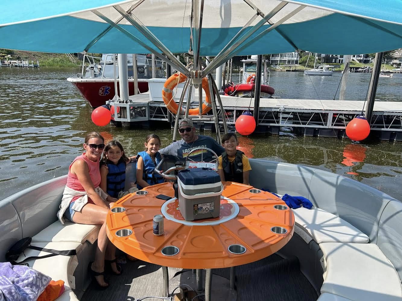 Family riding a donut boat rental in Saugatuck Michigan with kids wearing life jackets