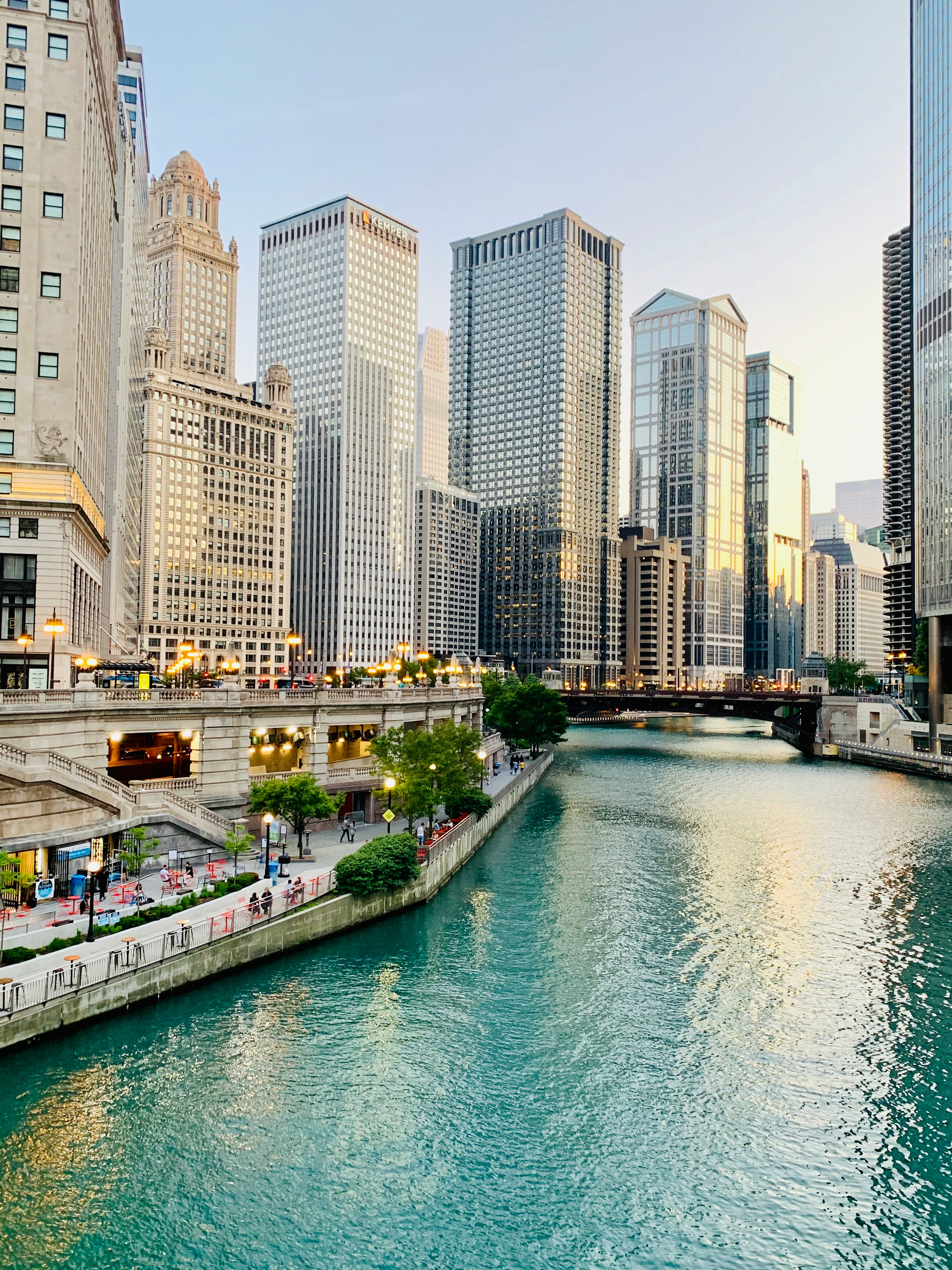Chicago Riverwalk with downtown buildings and the Chicago River at sunset