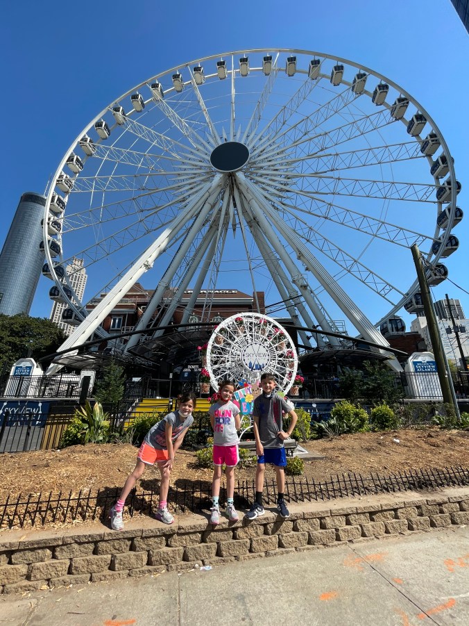 Kids enjoying a ride on the SkyView Atlanta Ferris wheel overlooking downtown Atlanta at night.