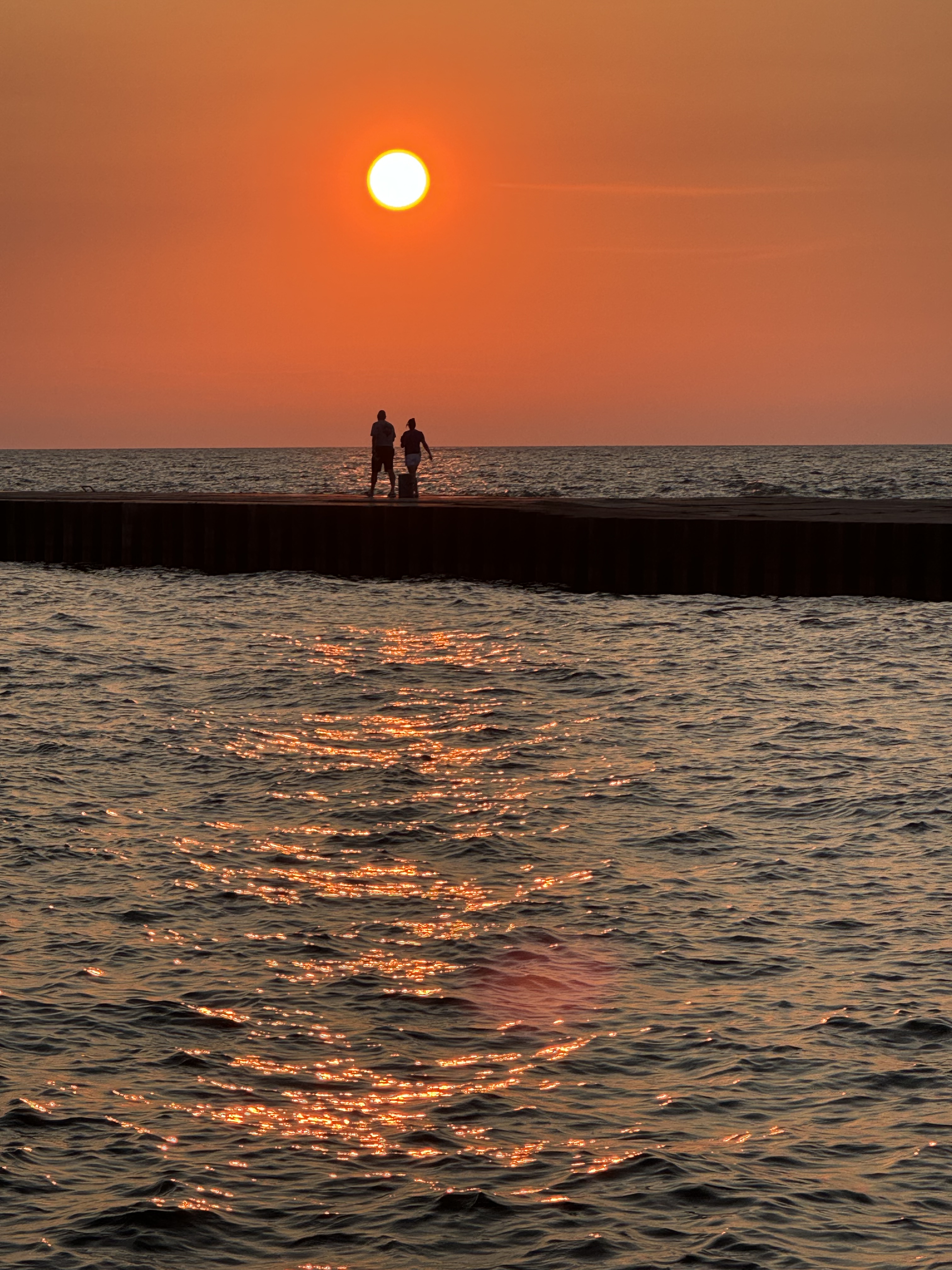 South Haven Pier Sunset Orange sunset over Lake Michigan with people sitting on the South Haven pier.