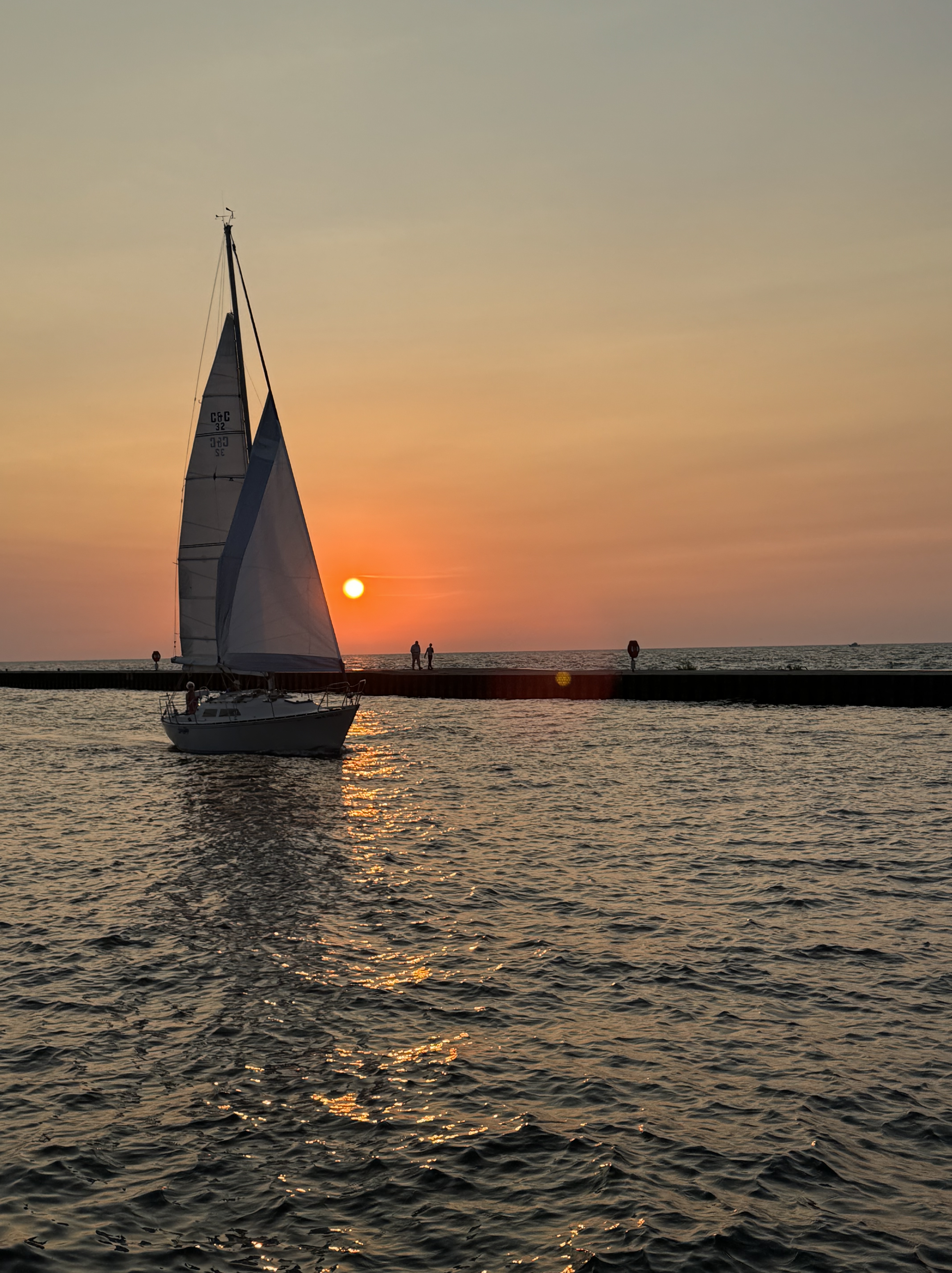 Lake Michigan sunset with sailboat and orange sky during a family vacation in Michigan