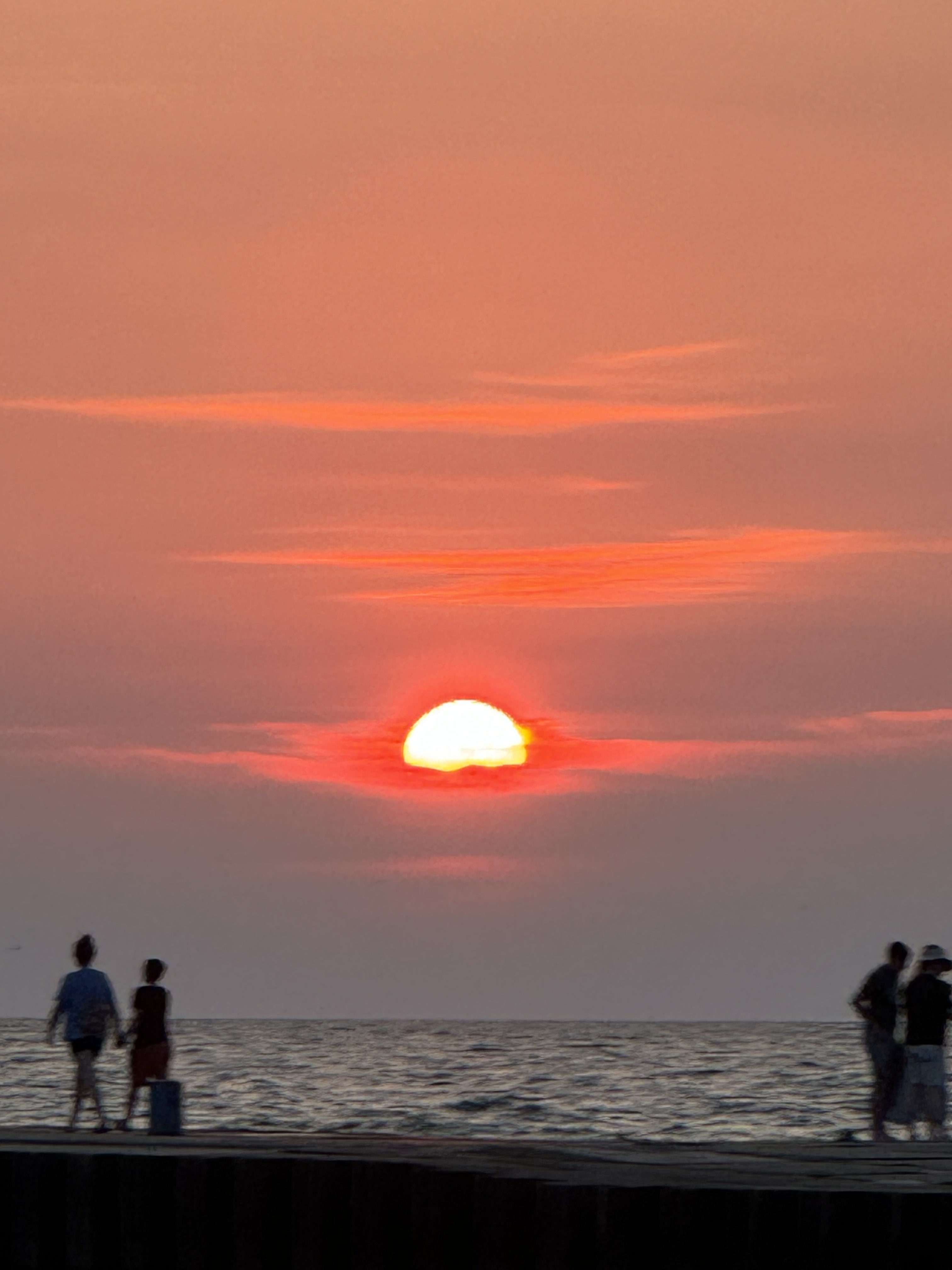 South Haven Sunset Over Lake Michigan Pink and orange sunset over Lake Michigan with people walking along the South Haven pier.