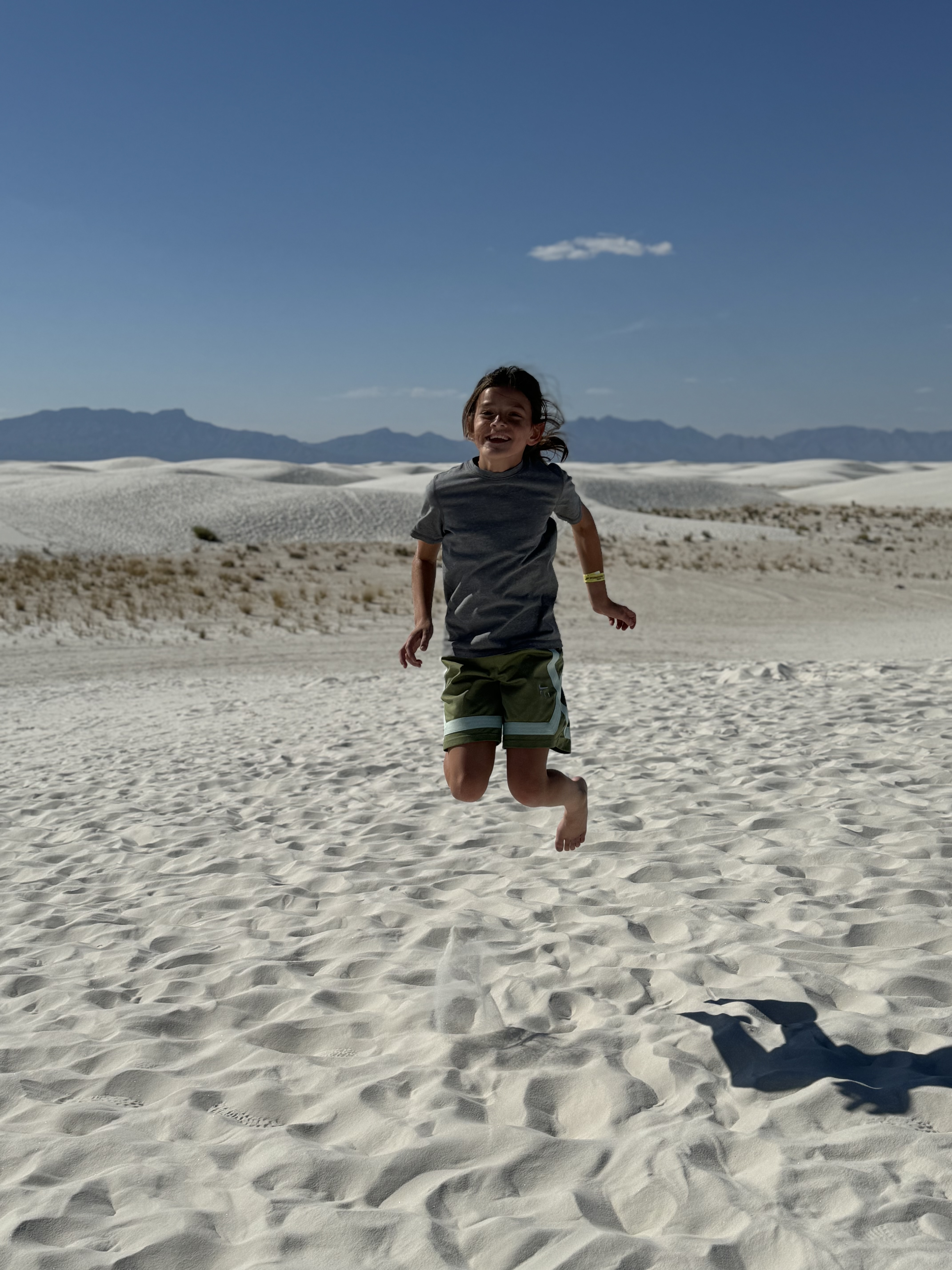 Child jumping in the white sand dunes at White Sands National Park