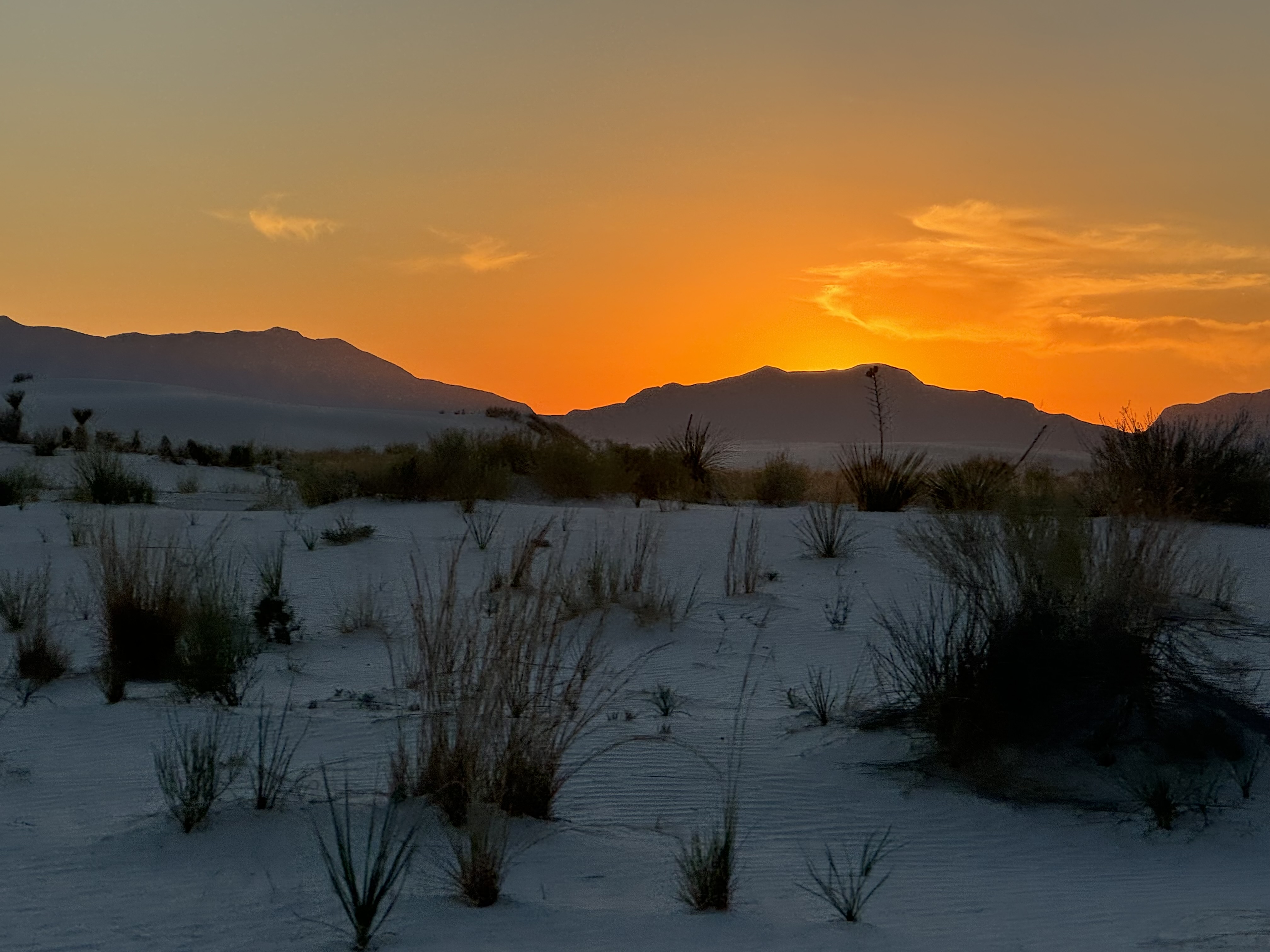 Sunset over the white sand dunes and mountains at White Sands National Park in New Mexico