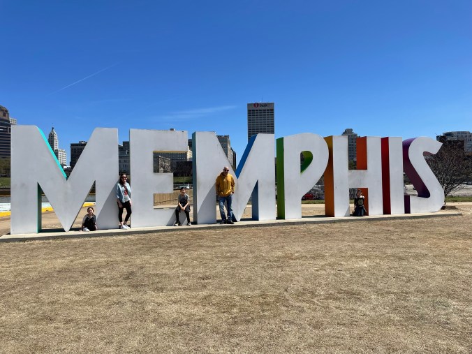 Kids posing beneath the Memphis sign during a family road trip through Tennessee