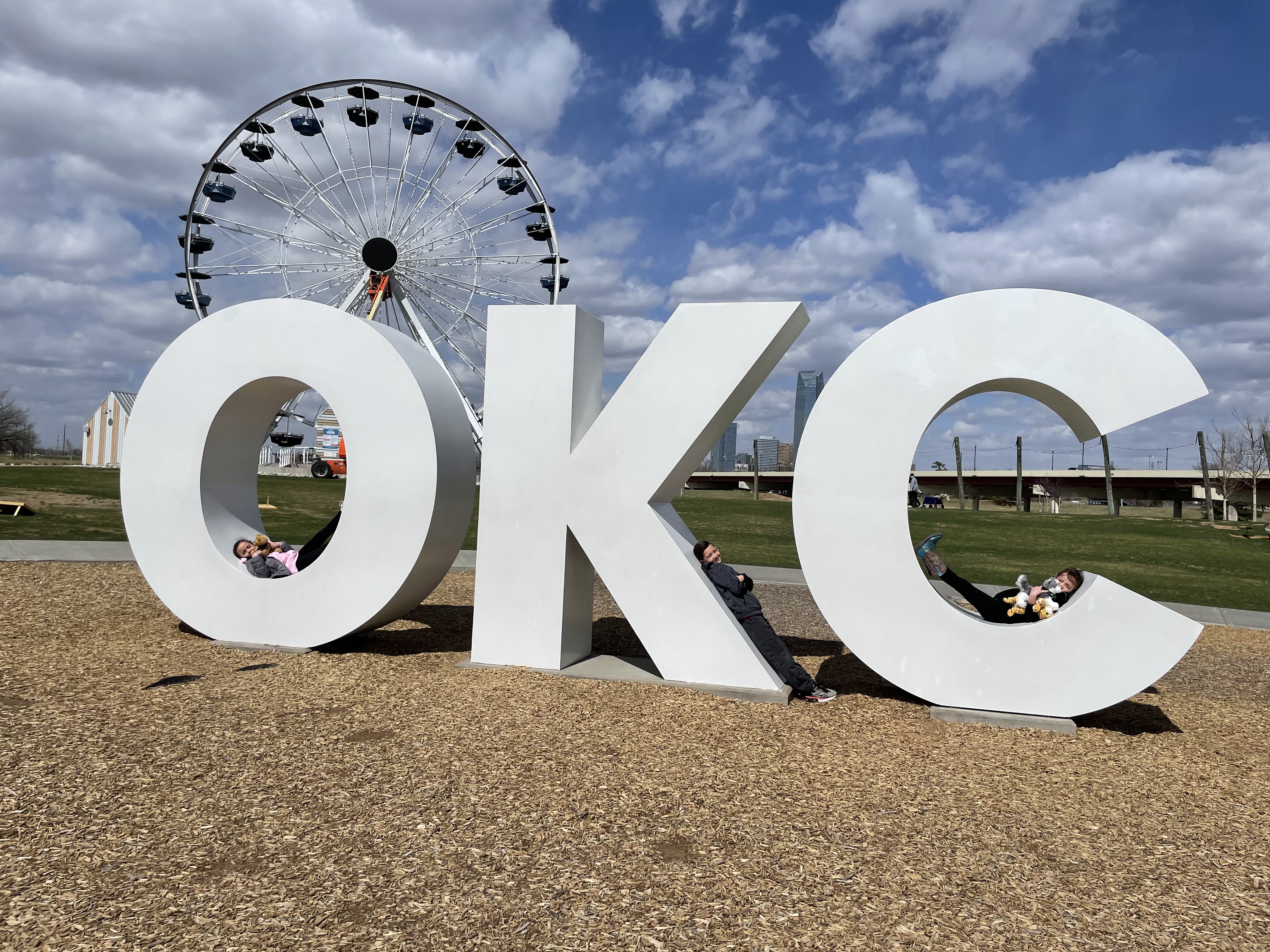 Kids posing by the Oklahoma City sign during a family road trip