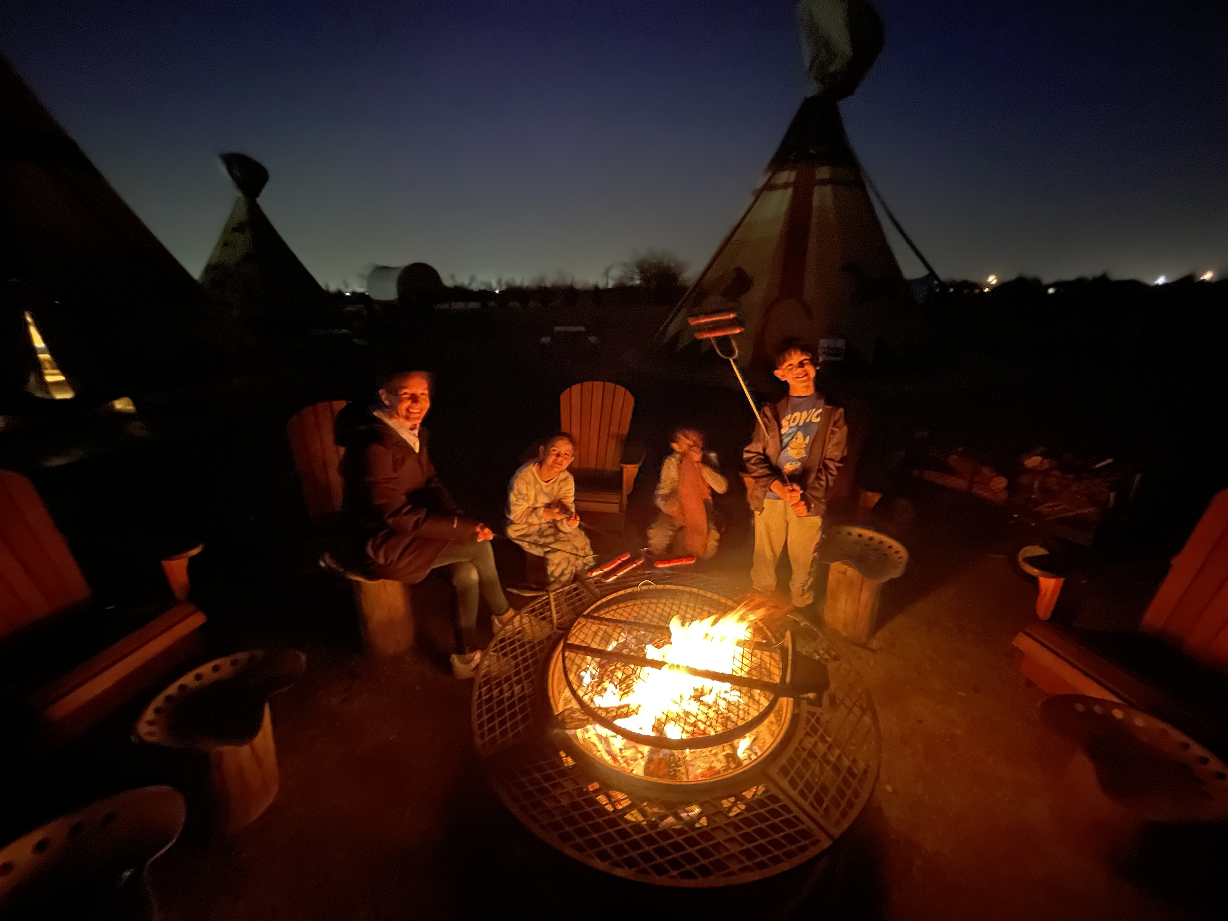 Kids roasting hotdogs & marshmallows by the fire at Orr Family Farm teepees