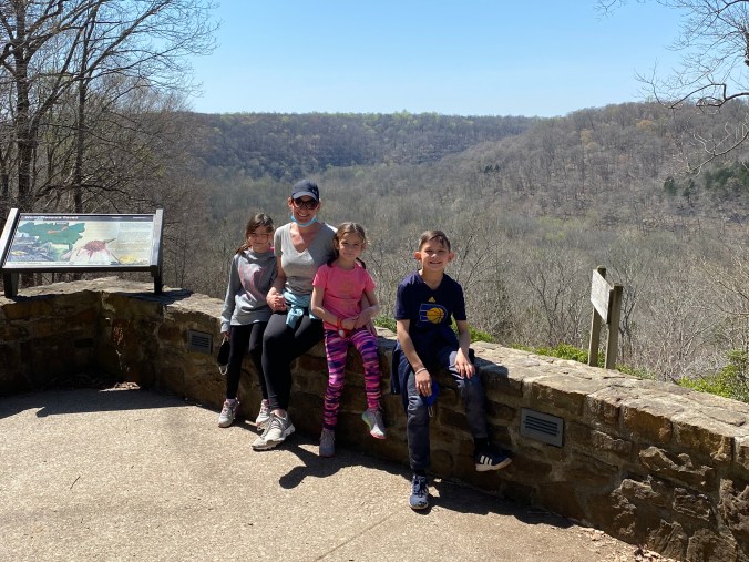 Family standing at a scenic overlook at Mammoth Cave National Park in Kentucky during a family road trip