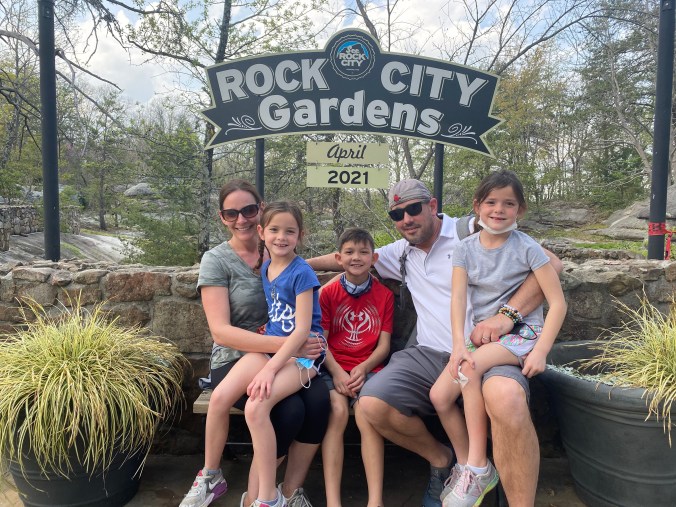 Family sitting beneath the Rock City Gardens sign on Lookout Mountain in Tennessee