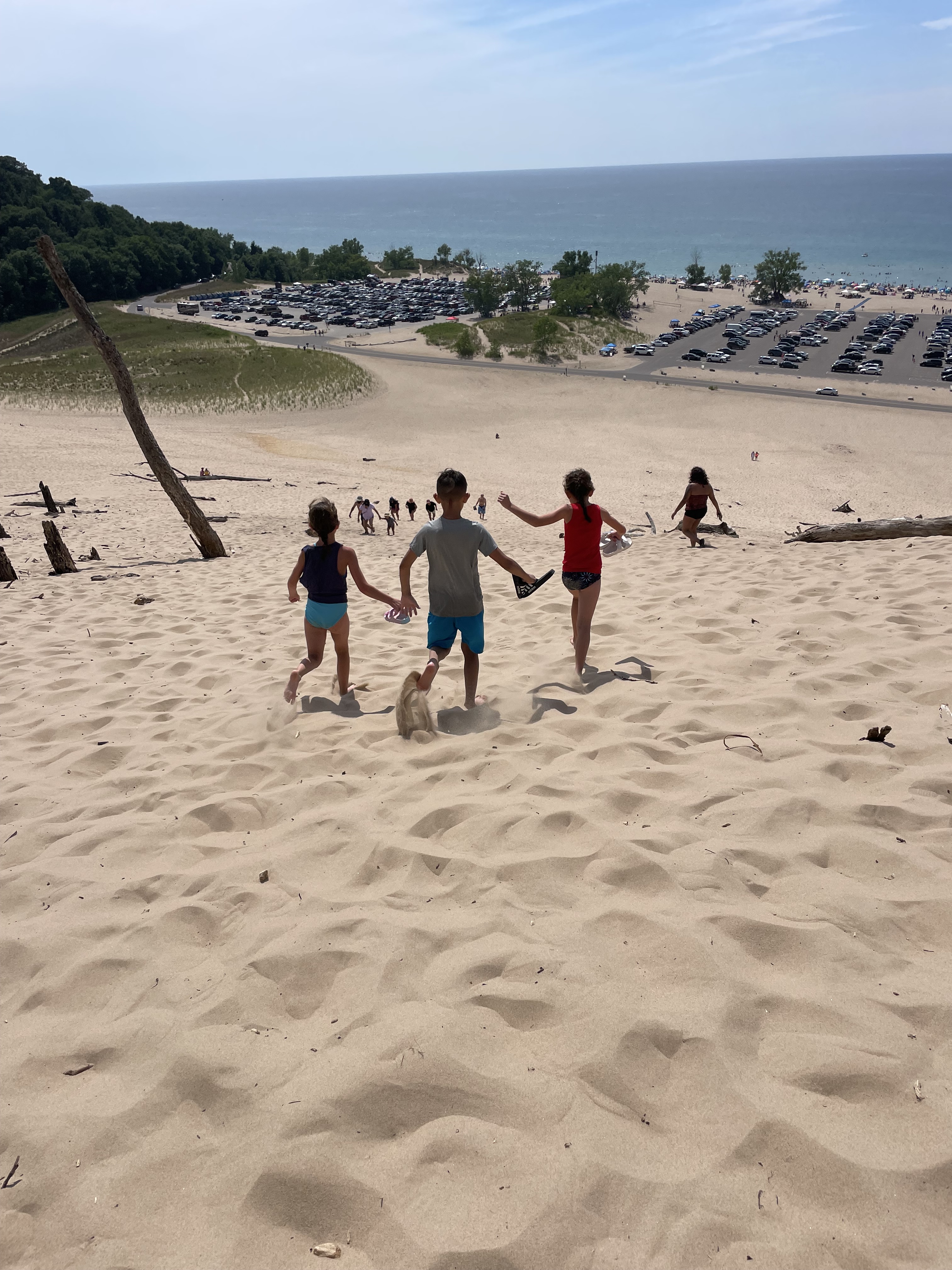 Kids running down the giant sand dunes at Warren Dunes State Park overlooking Lake Michigan.