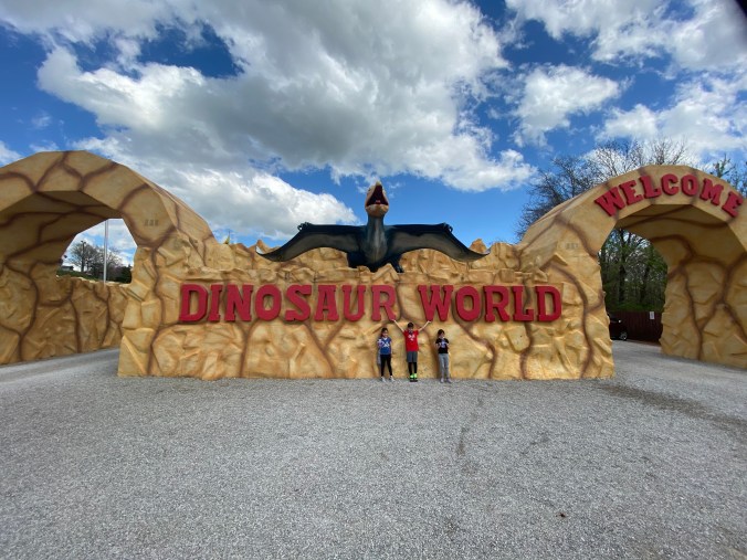 Kids standing in front of the Dinosaur World sign in Cave City Kentucky during a family road trip