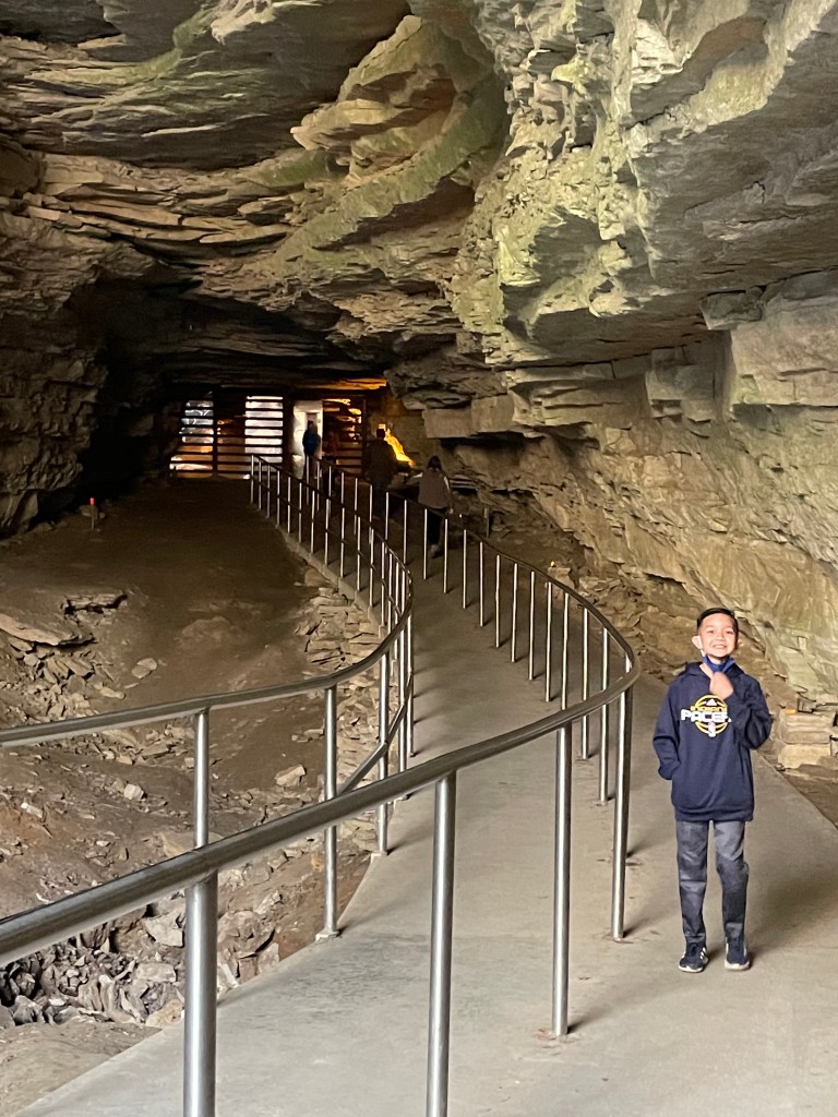 Boy walking through large underground passage inside Mammoth Cave National Park