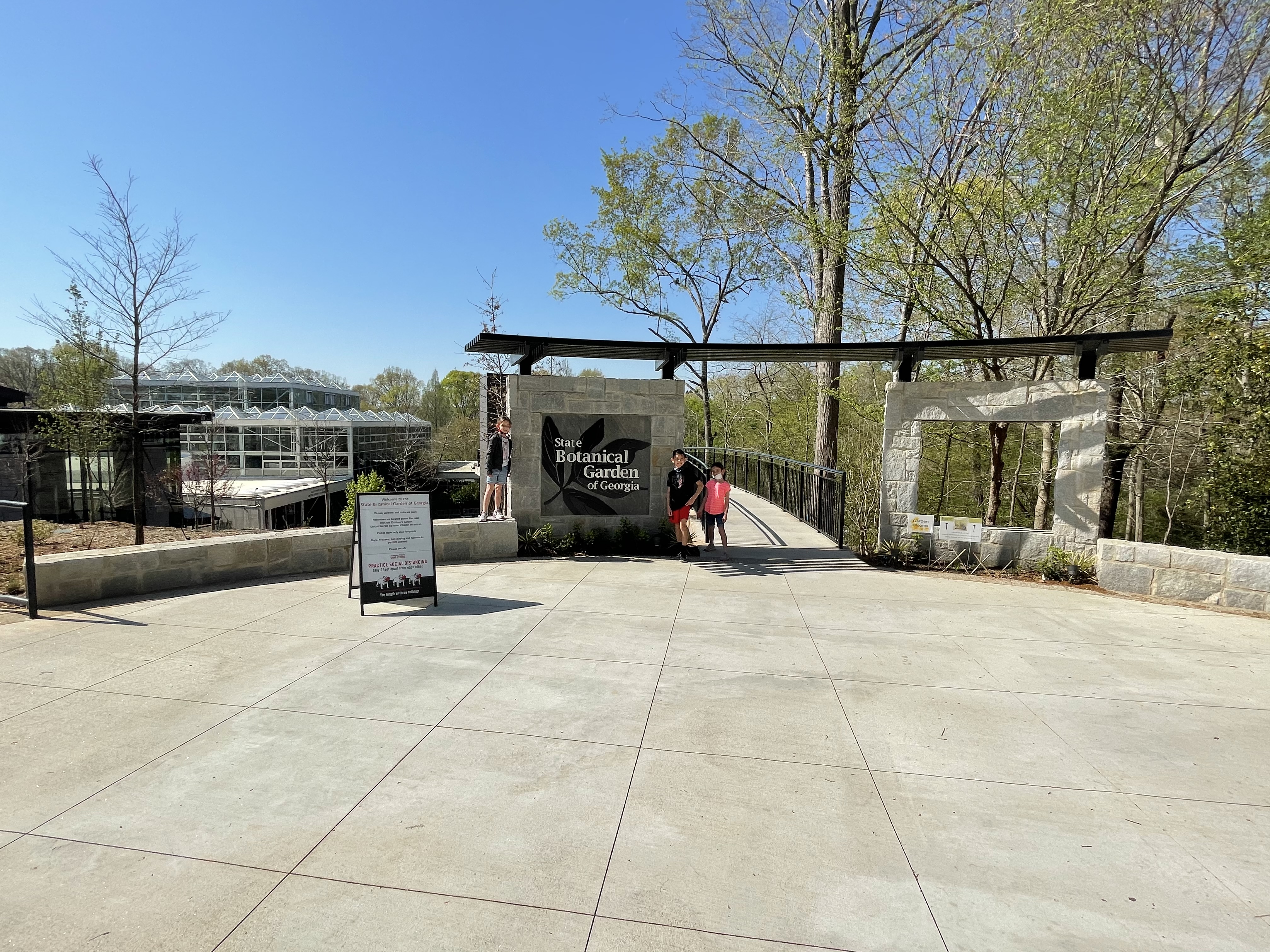 Kids standing near the entrance sign at the State Botanical Garden of Georgia during a family trip