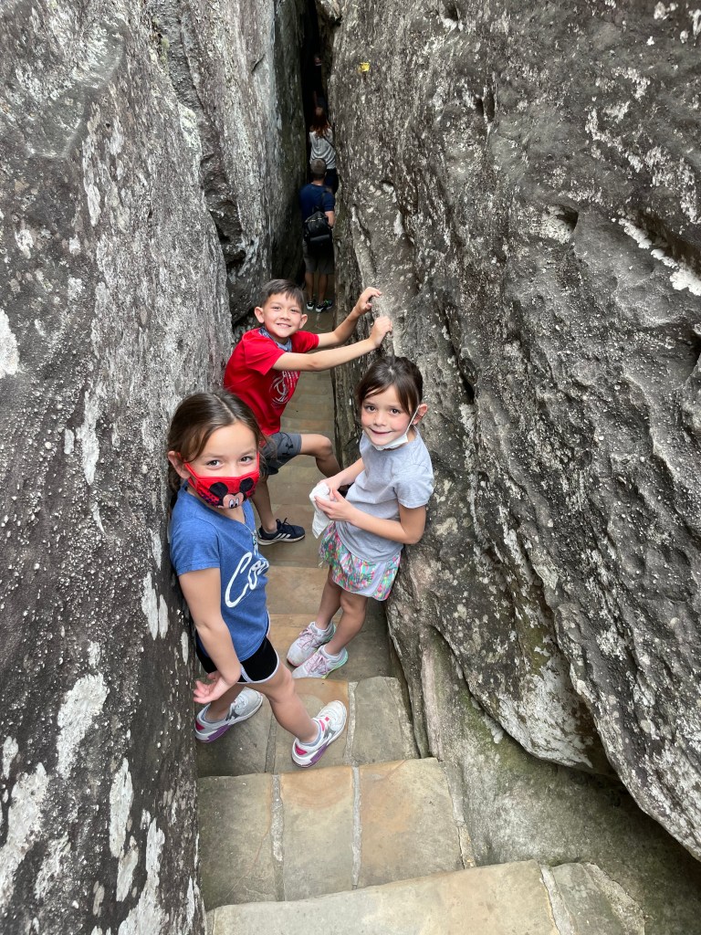 Kids walking through a narrow rock passage at Rock City Gardens on Lookout Mountain in Tennessee