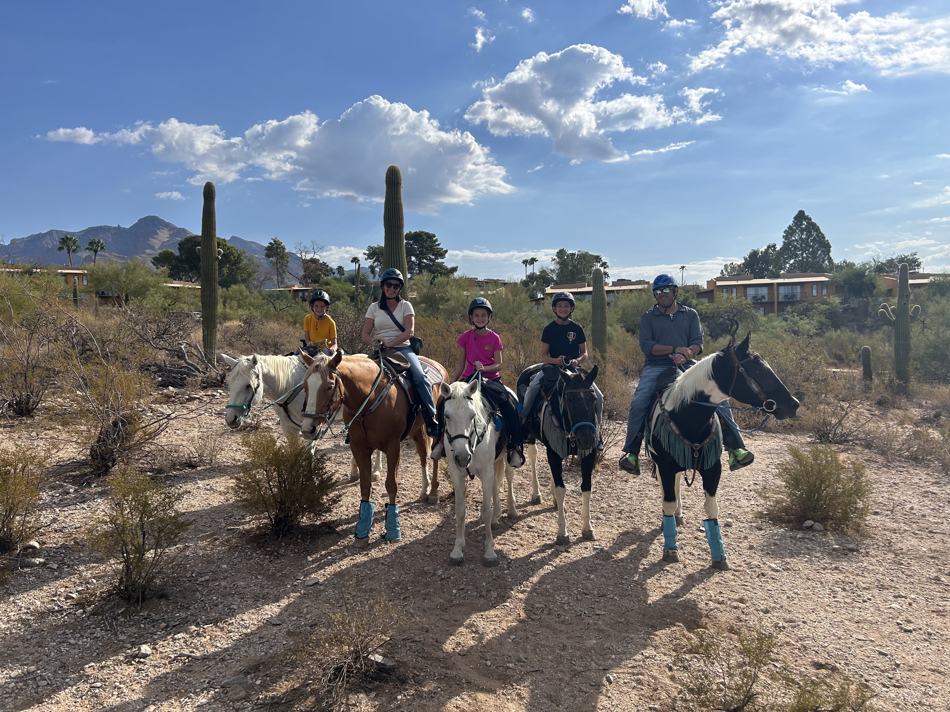 Family horseback riding through the desert in Tucson Arizona with cactus and mountain views