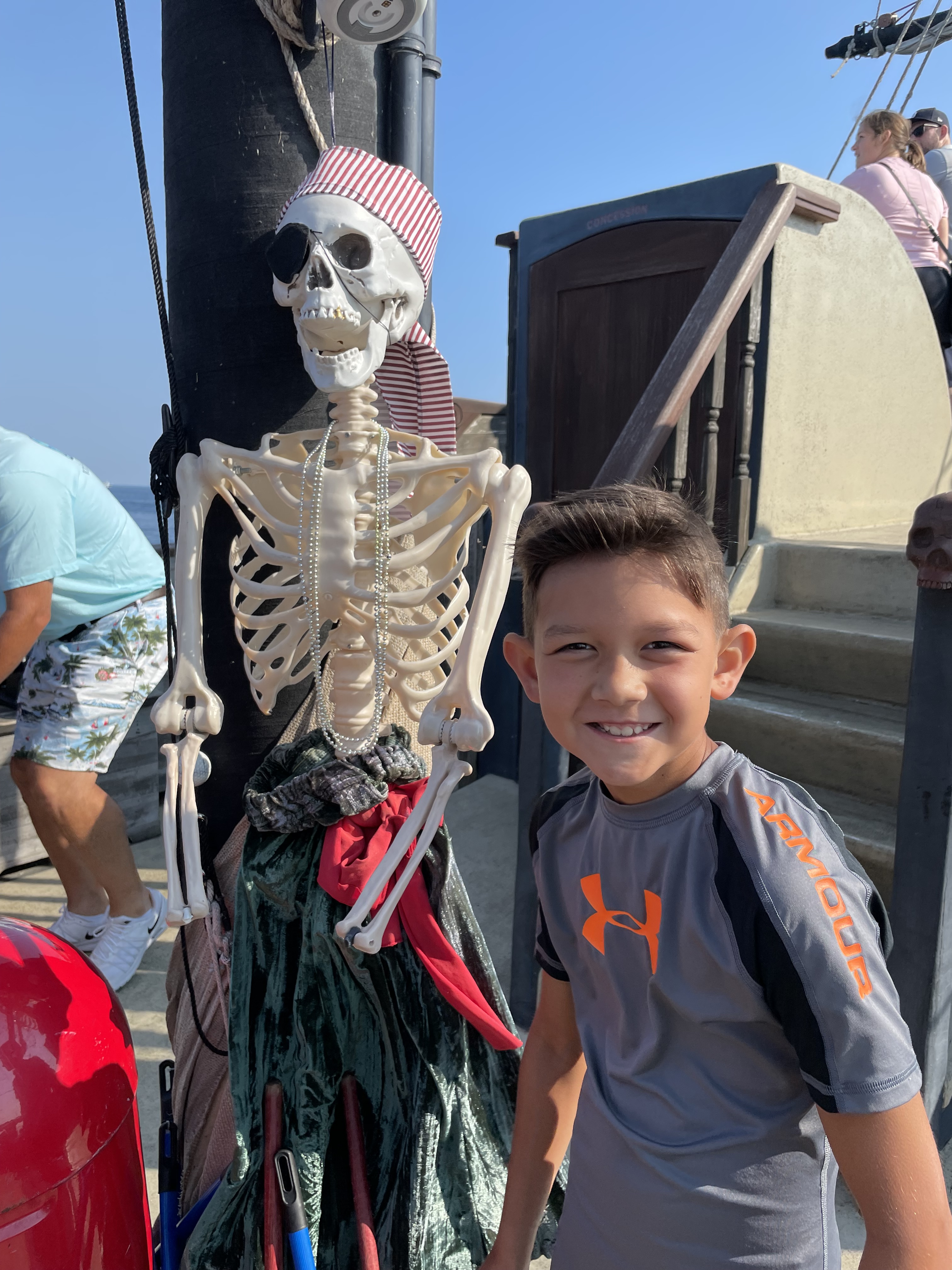 Child standing next to a pirate skeleton decoration on the Good Fortune Pirate Ship ferry