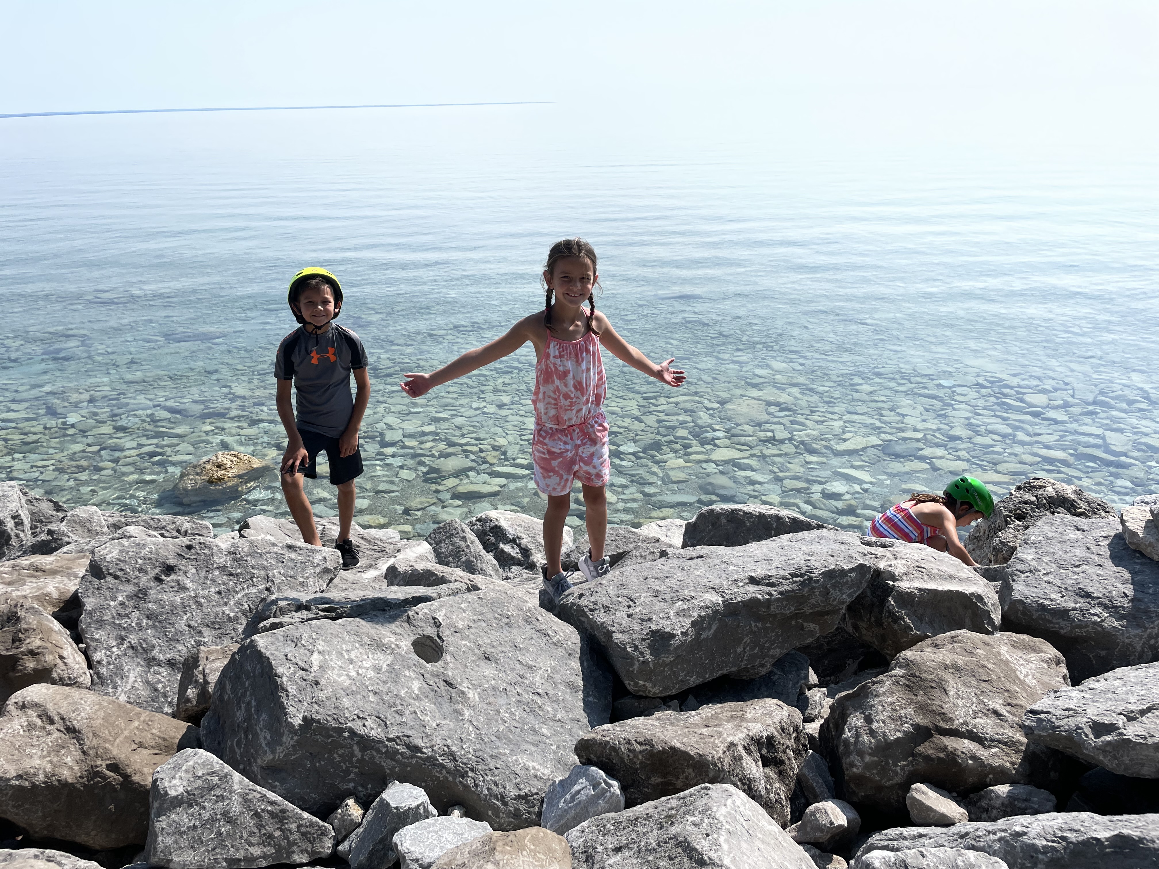 Kids playing along the rocky Lake Huron shoreline on Mackinac Island during a family bike ride