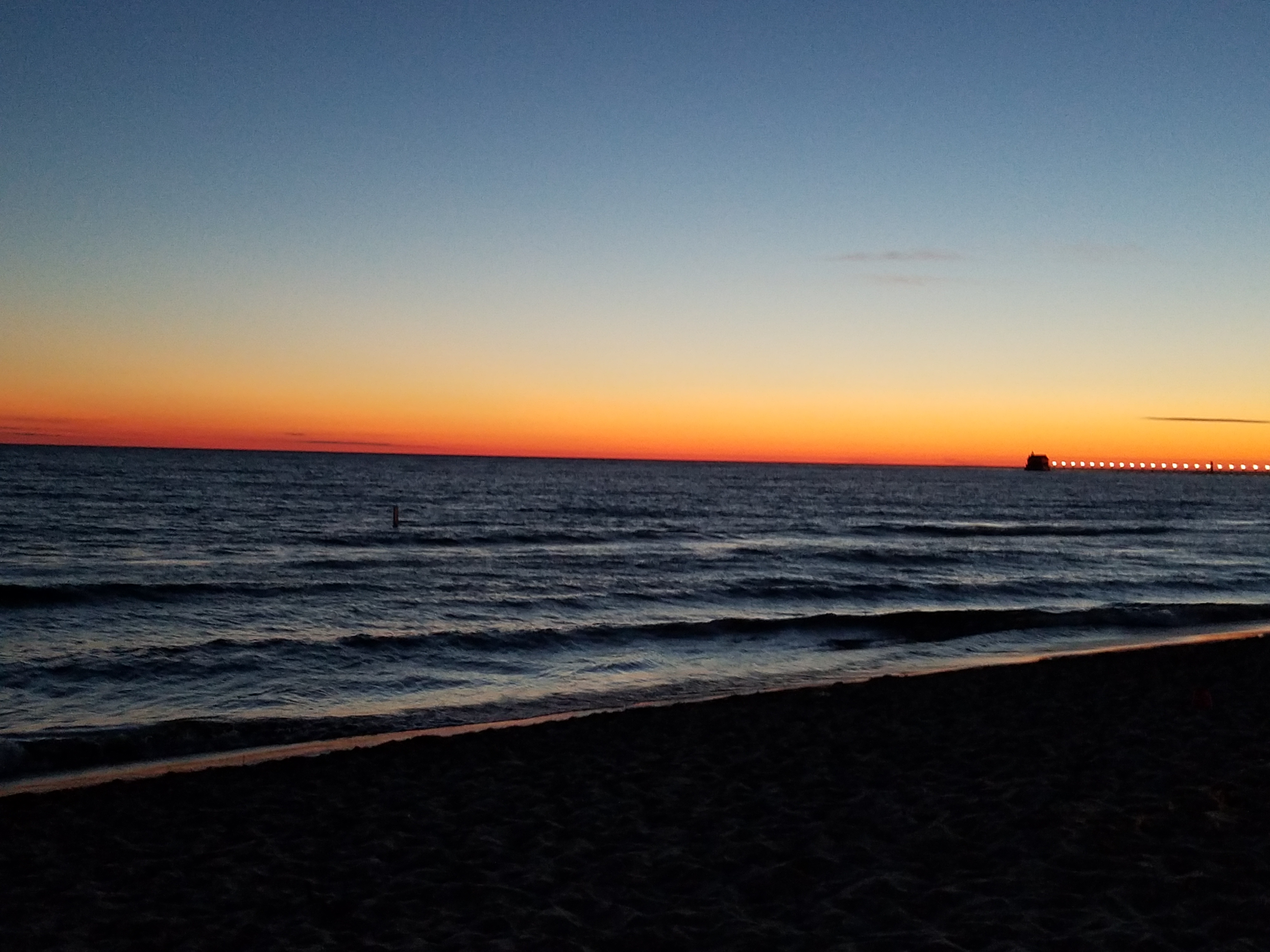 Sunset over Lake Michigan near the Grand Haven pier and lighthouse.