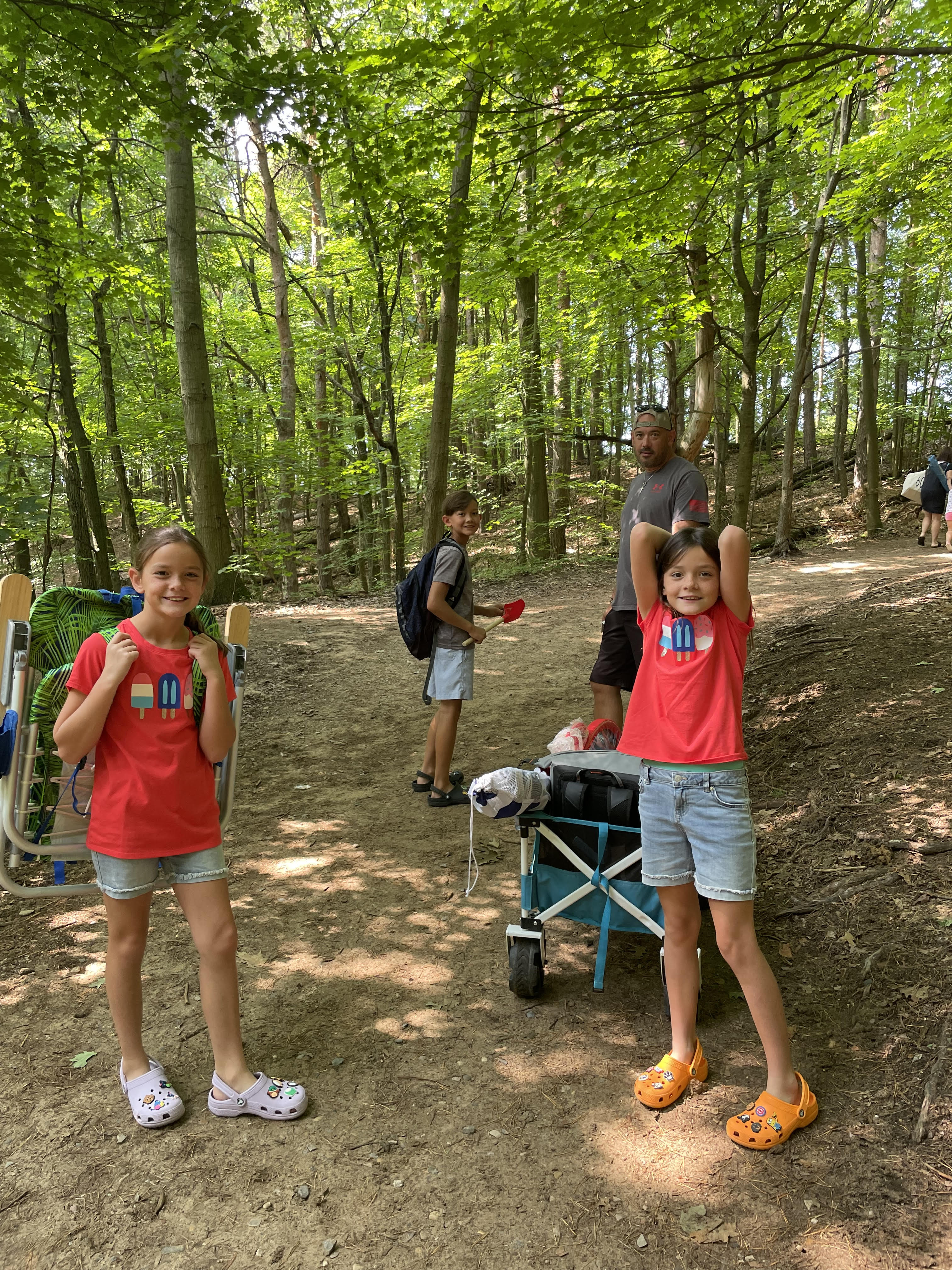 Kids hiking through wooded trails carrying beach gear at Saugatuck Dunes State Park in Michigan
