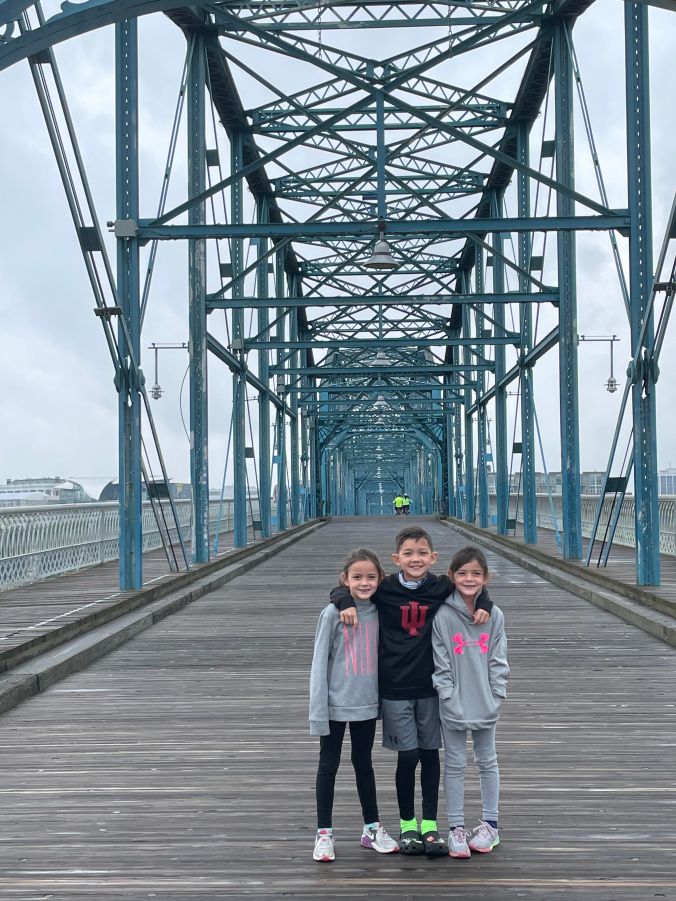 Family standing on the Walnut Street Bridge in Chattanooga, Tennessee with the steel bridge structure surrounding them.
