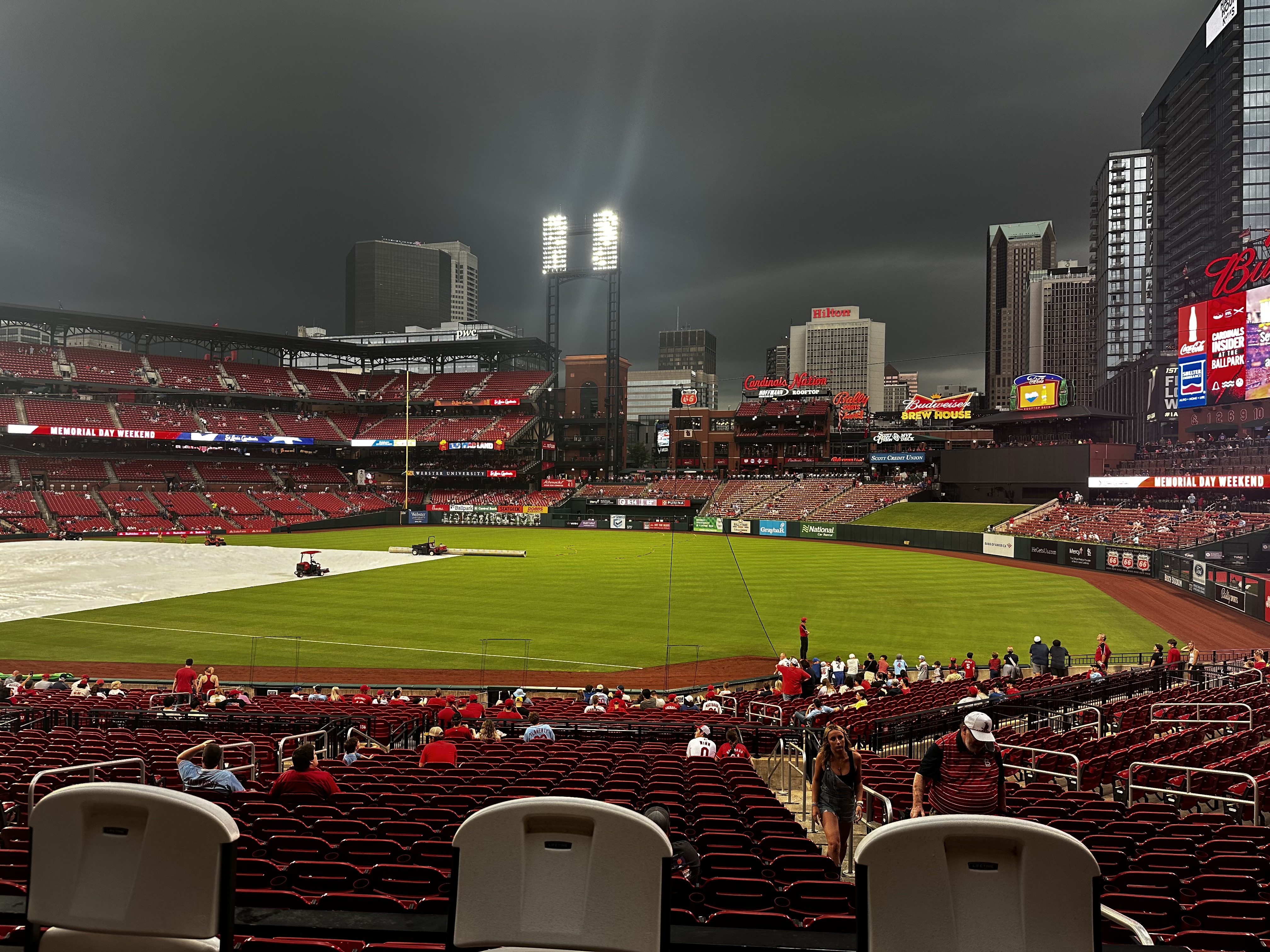 Dark storm clouds over Busch Stadium with the field covered by a tarp during a weather delay at a St. Louis Cardinals game